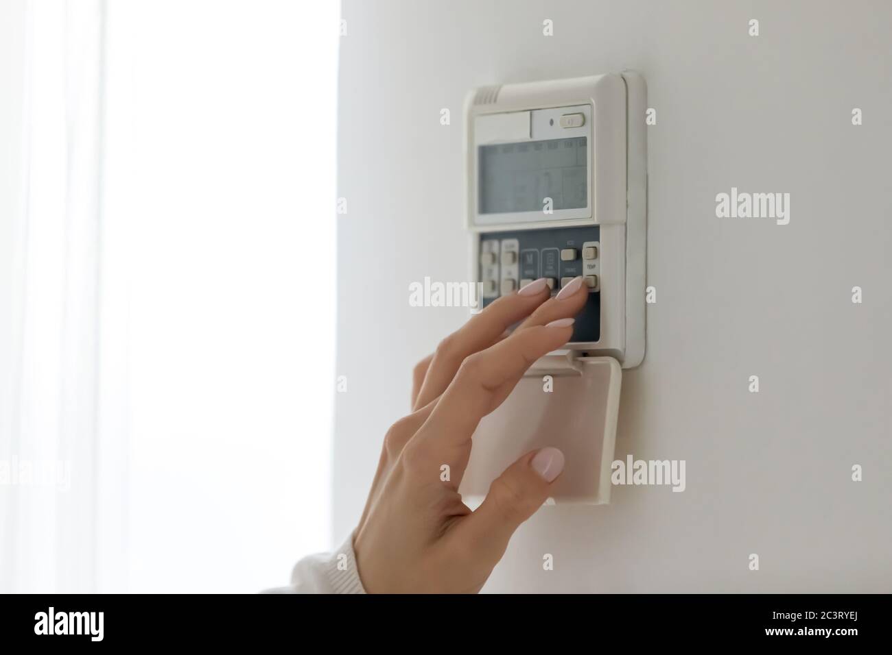 Female fingers set comfortable temperature at home use digital thermostat Stock Photo