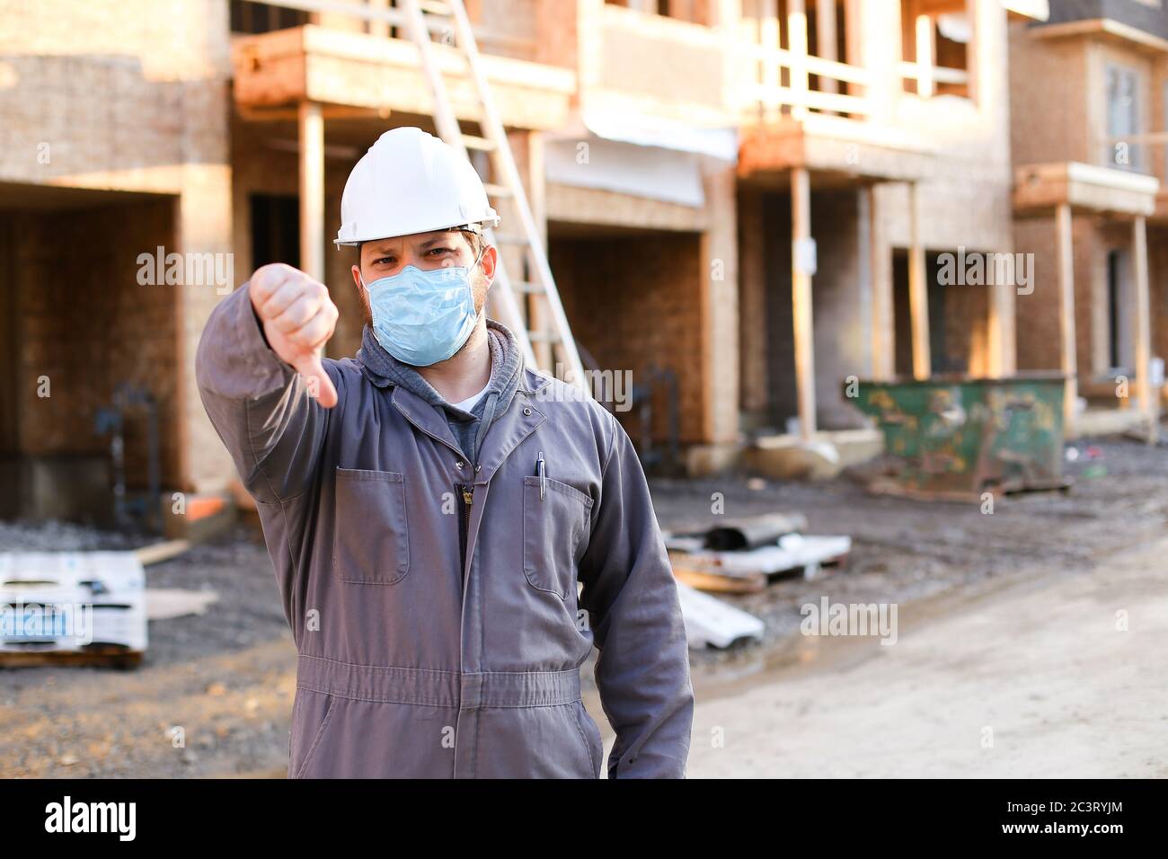 Foreman wearing mask and hardhat at construction site showing thumbs ...
