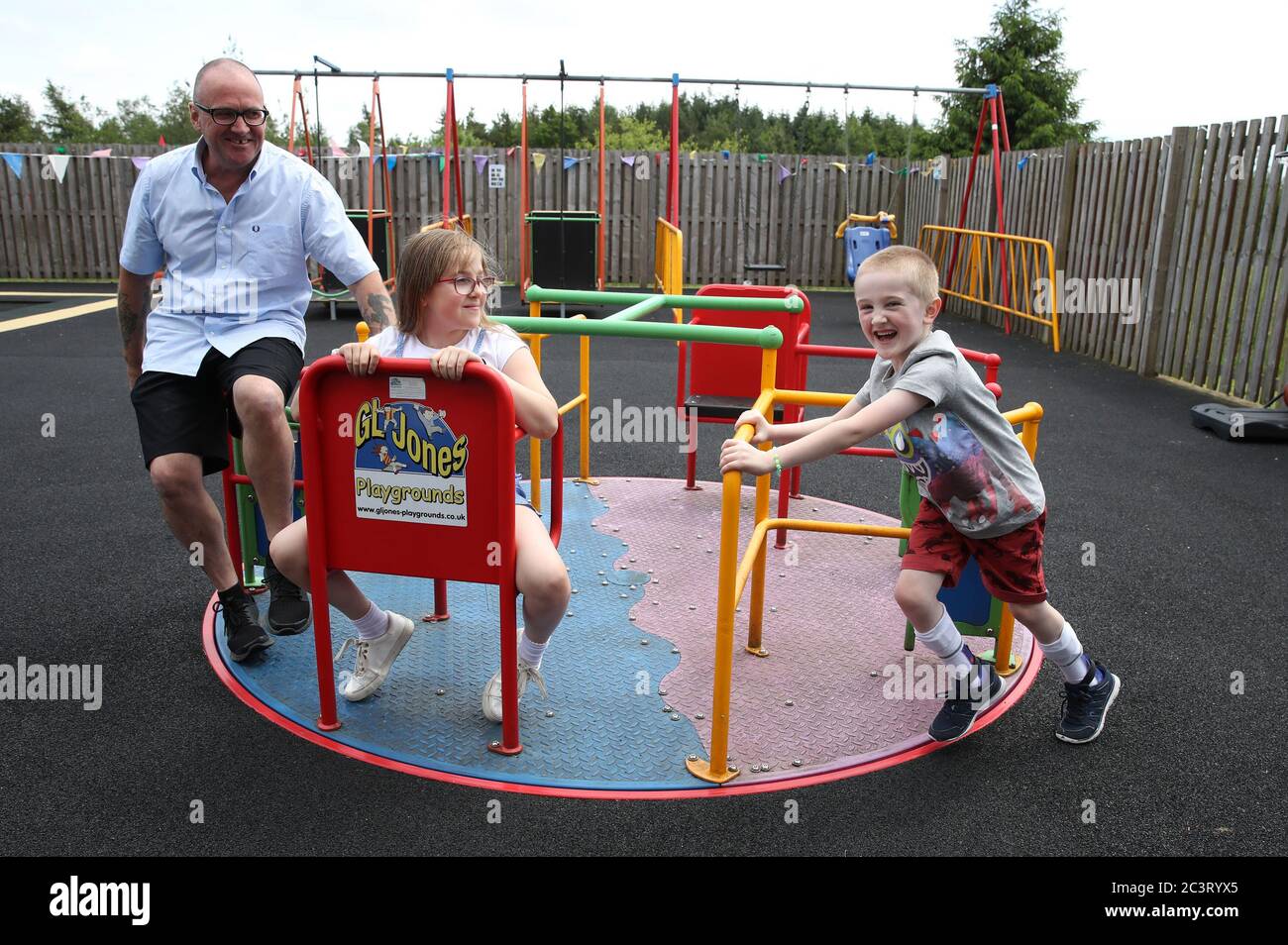 Callum McMichael pushes his sister Laura and father Barry on the roundabout in the outside therapy area at the Craighalbert Centre. Coronavirus adaptations have been installed at the Scottish Centre for Children with Motor Impairments, Craighalbert Centre, Cumbernauld, as Scotland continues gradually lifting coronavirus lockdown measures. Stock Photo