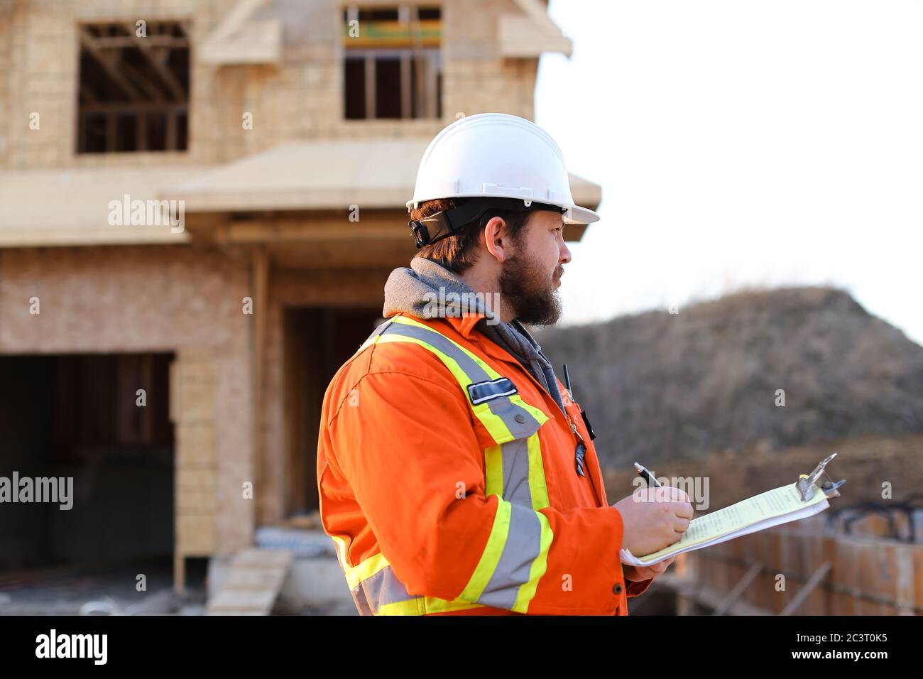 European foreman writing in notebook on construction site. Stock Photo