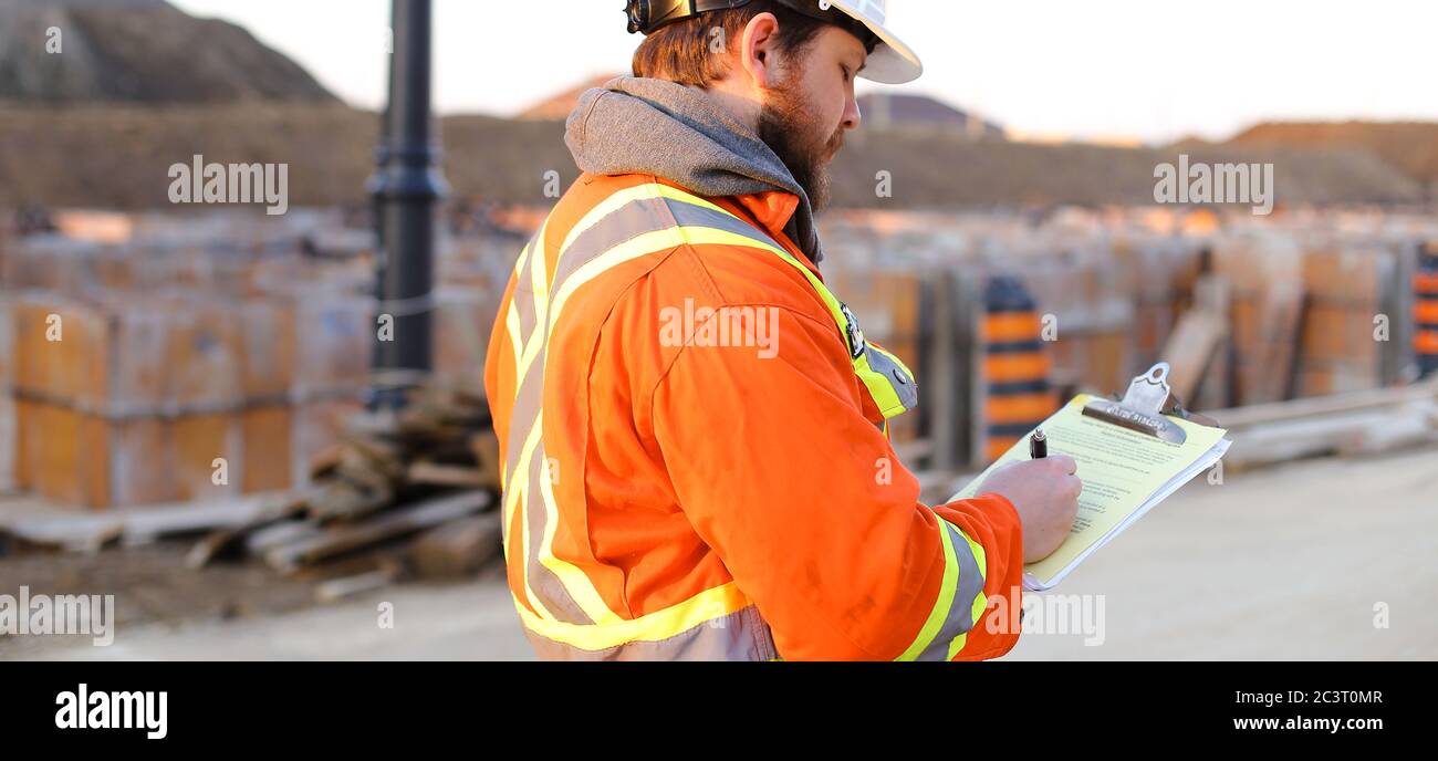 Banner of inspector in orange workwear with blueprints on construction site. Stock Photo