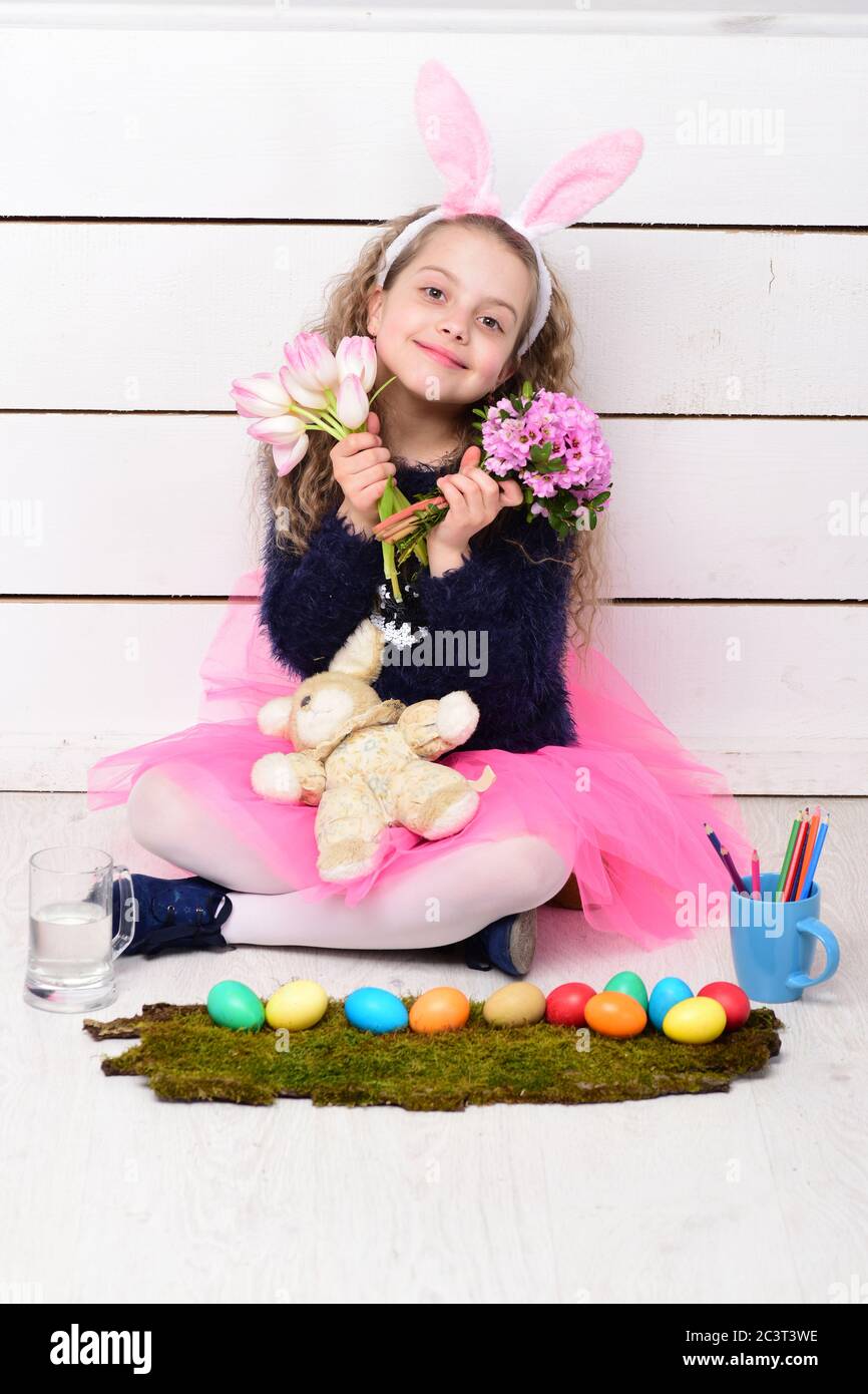 happy easter holiday, cute girl in bunny ears, small child with curly hair,  rabbit or hare toy, pencils, tulip flower, colorful painted eggs on white  wooden background, womens or mothers day spring