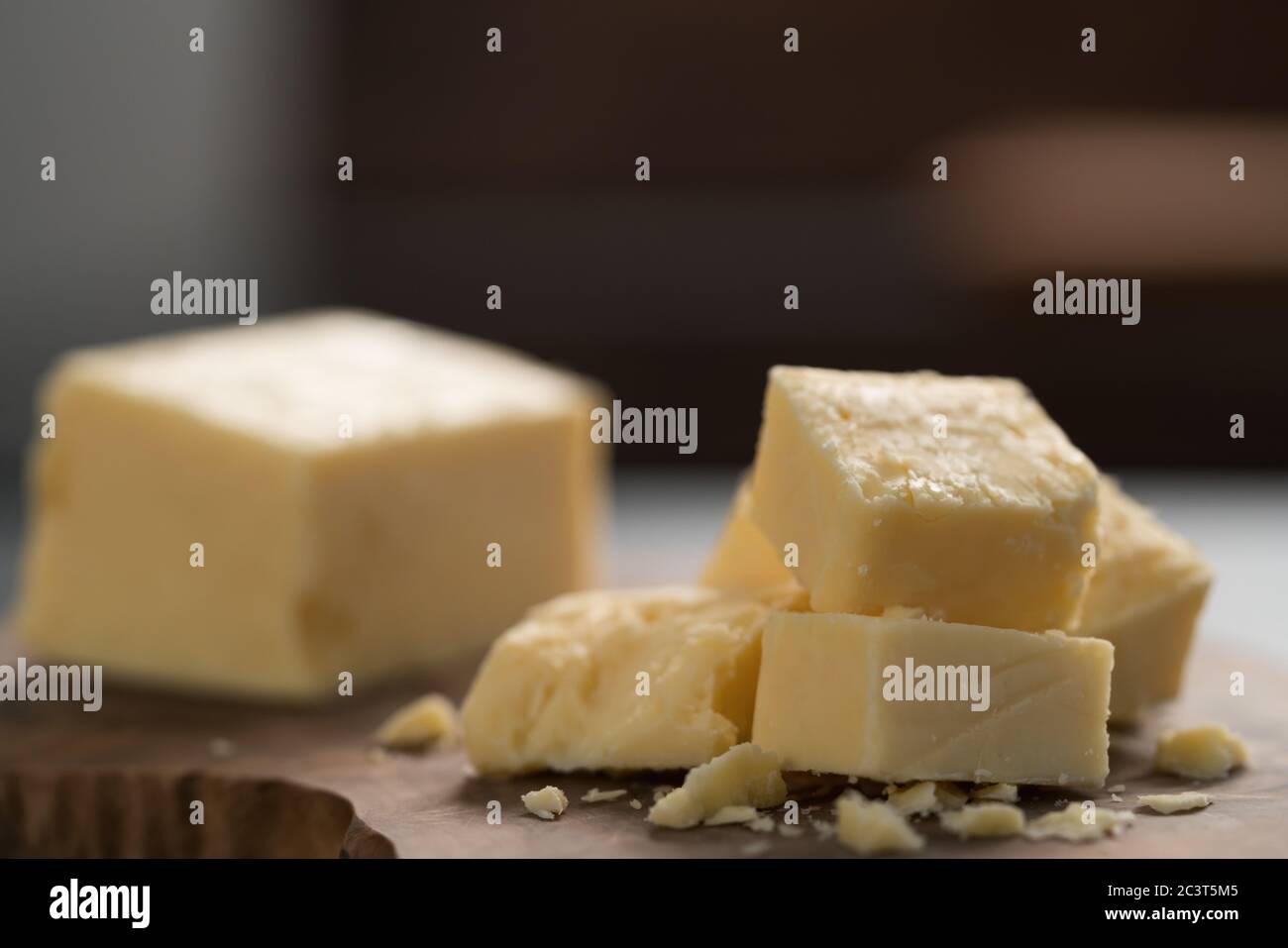 White cheddar cheese pieces on olive wood board Stock Photo