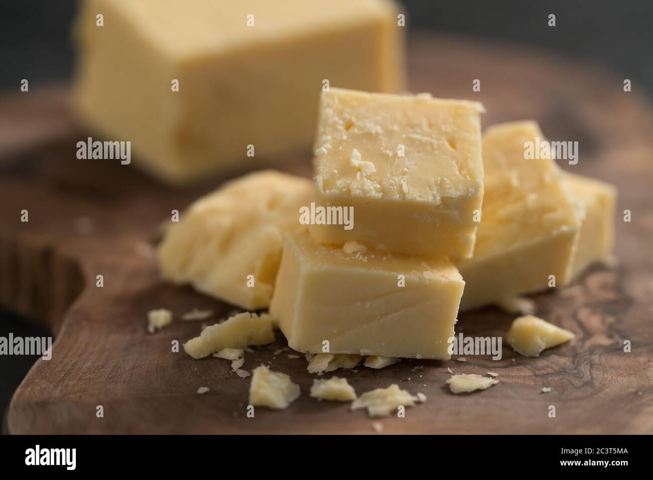 White cheddar cheese pieces on olive wood board Stock Photo