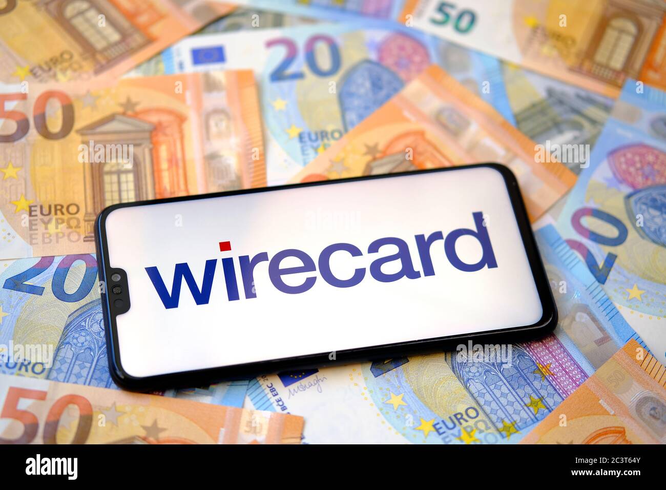 Wirecard logo on smartphone and euro banknotes on the blurred background. Concept. Stock Photo
