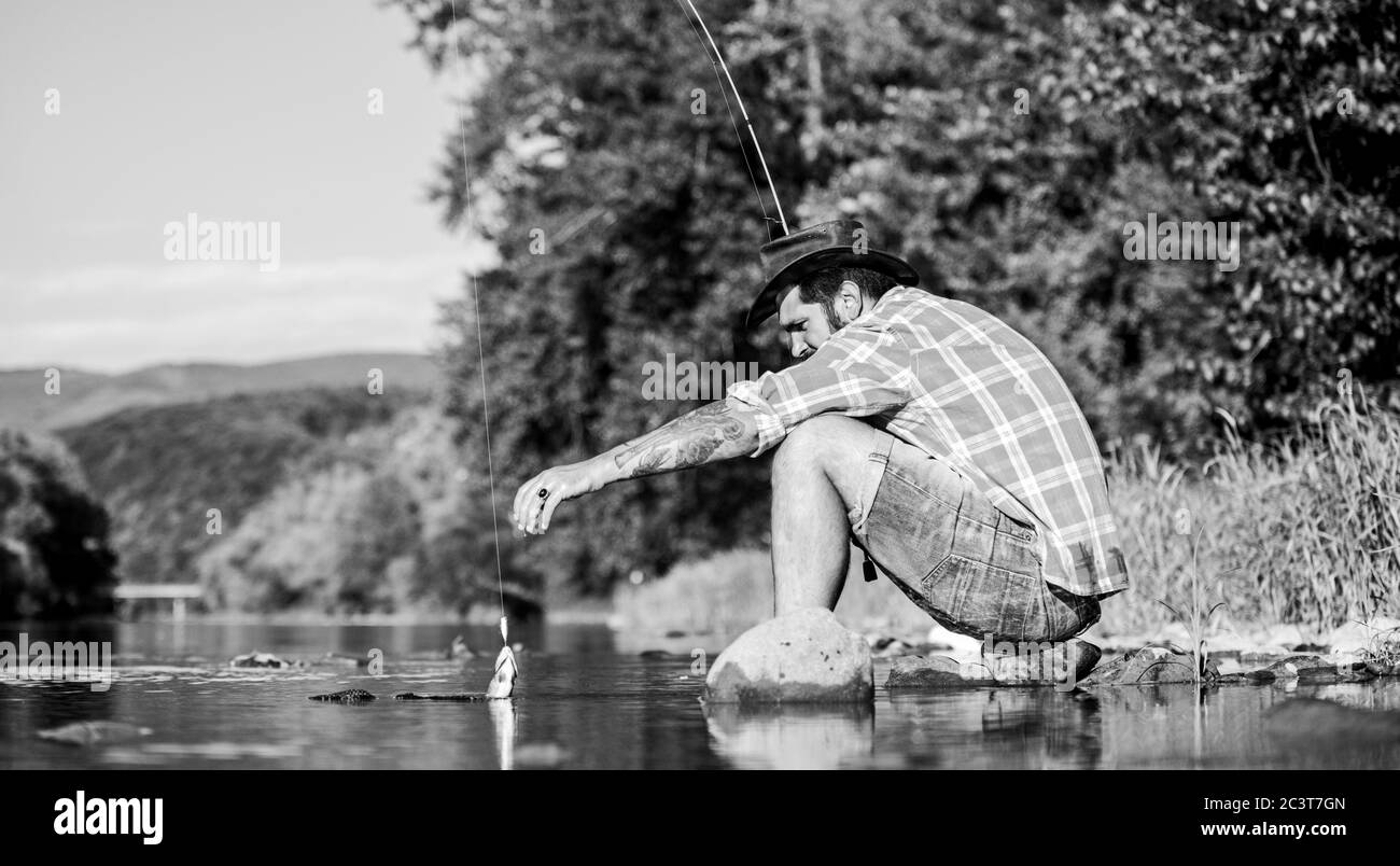 Gone Fishing. successful fisherman in lake water. hipster fishing with spoon-bait. big game fishing. relax on nature. fly fish hobby. Summer activity. mature bearded man with fish on rod. Stock Photo