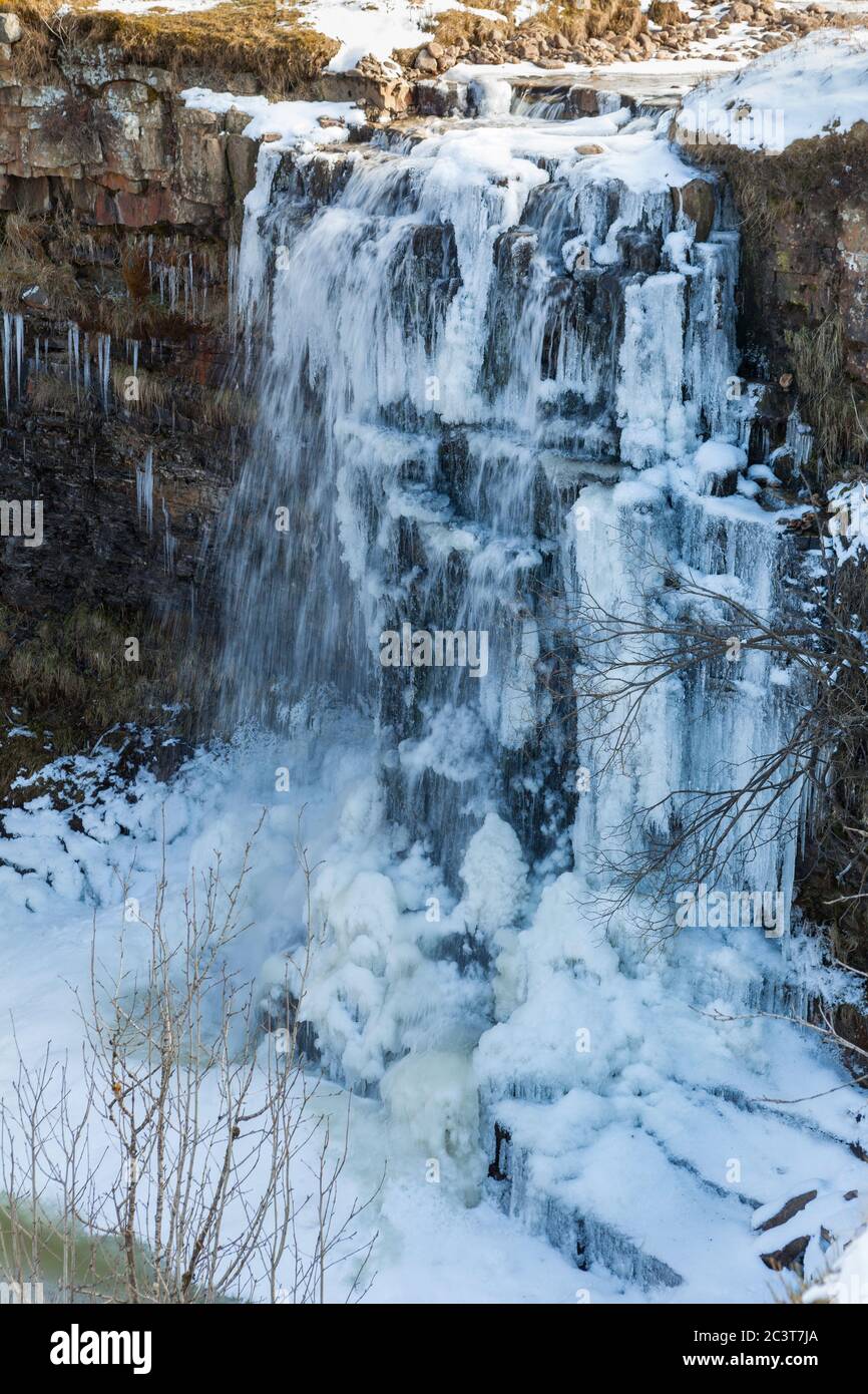 A winter view of an icy and partly frozen Hellgill Force, an attractive waterfall in the Yorkshire Dales National Park Stock Photo