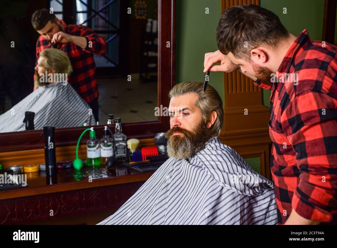 Professional hairstylist in barbershop interior. Hipster client getting ...