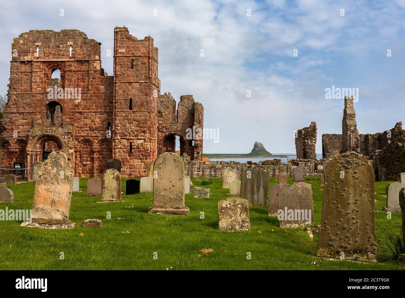 Cemetery, the ruins of Lindisfarne Priory and in the distance, Lindisfarne Castle, Holy Island, Northumberland, England, UK Stock Photo