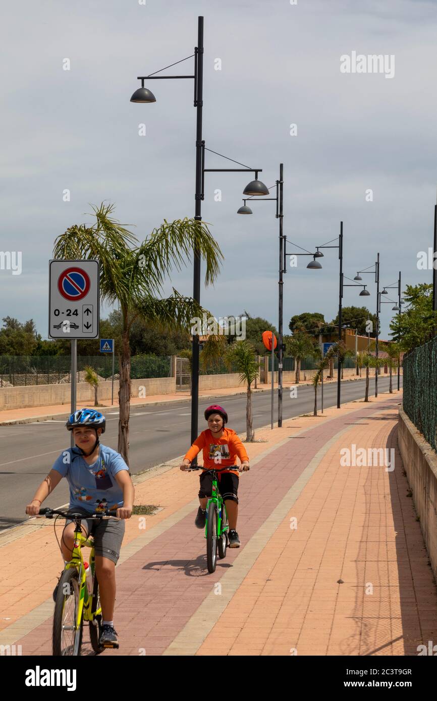 Kids safely cycling over a cycling path on the pavement , Marina di Cinisi, Palermo, Sicily Stock Photo
