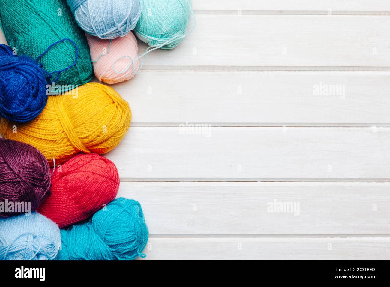 Bright colorful clews and crochet hooks on light wooden background Stock Photo