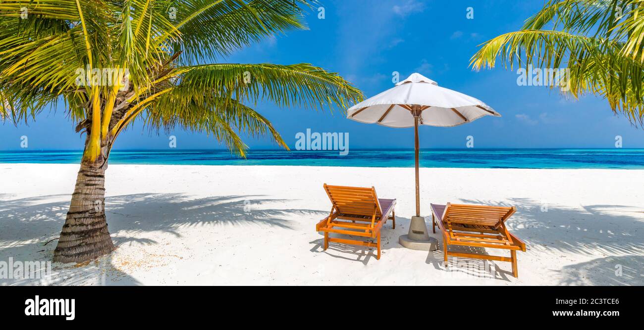 Luxury beach background with sun loungers and umbrellas and perfect sea view. Tranquil tropical beach scene for luxury travel and tourism concept Stock Photo