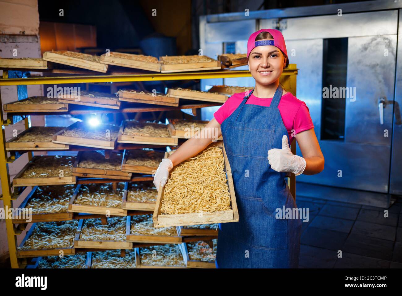 Make the noodles. Pasta factory. Spaghetti production. Raw pasta. Worker with a box of pasta