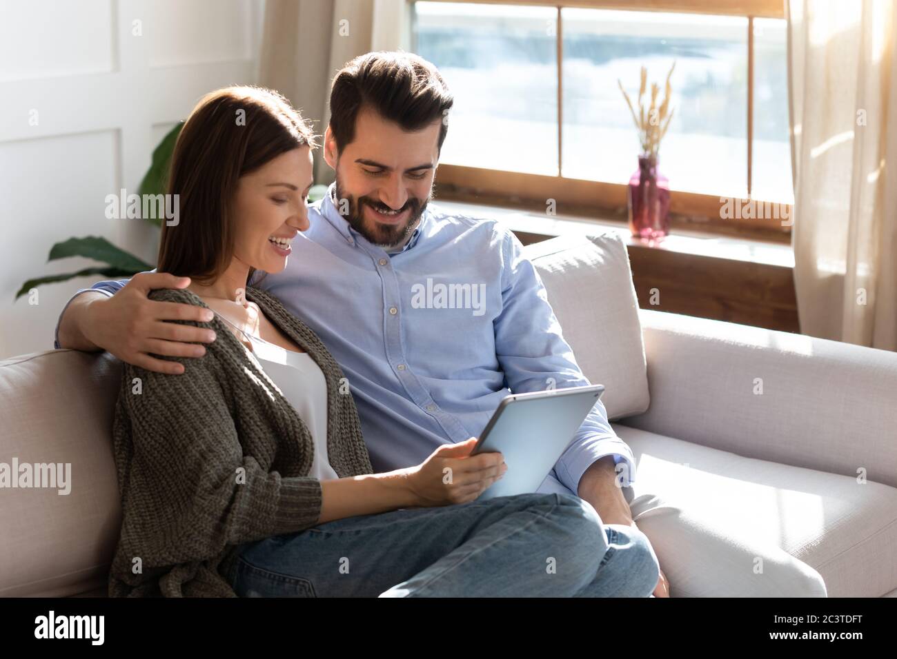 Smiling woman and man hugging, using electronic device together Stock Photo