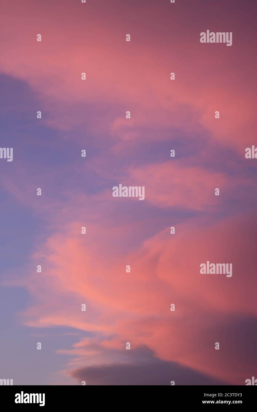 puesta de sol con coloridas nubes rosa claro con cielo azul en el fondo Stock Photo