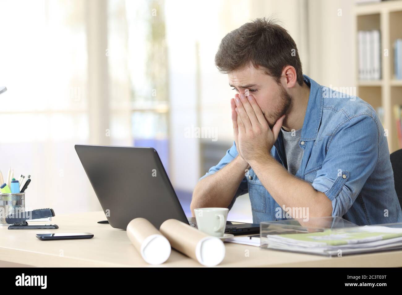 Worried entrepreneur man looking at laptop complaining sitting at the office Stock Photo