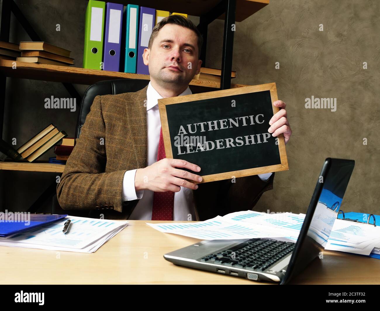 Authentic Leadership concept. Young businessman holds a black board. Stock Photo