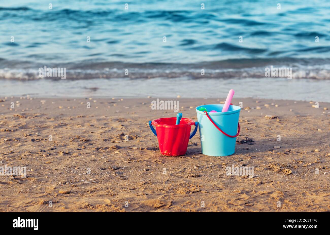 Child's bucket, spade and other toys in the sand on empty beach Stock Photo