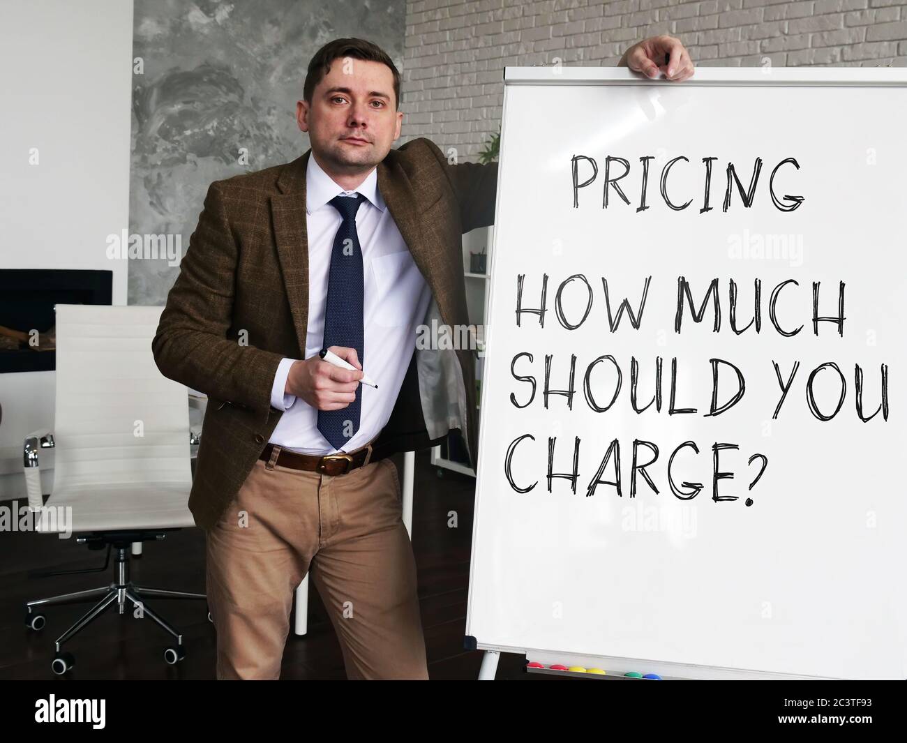 Pricing strategy - How Much Should You Charge. Business Advisor at the blackboard with the inscription. Stock Photo