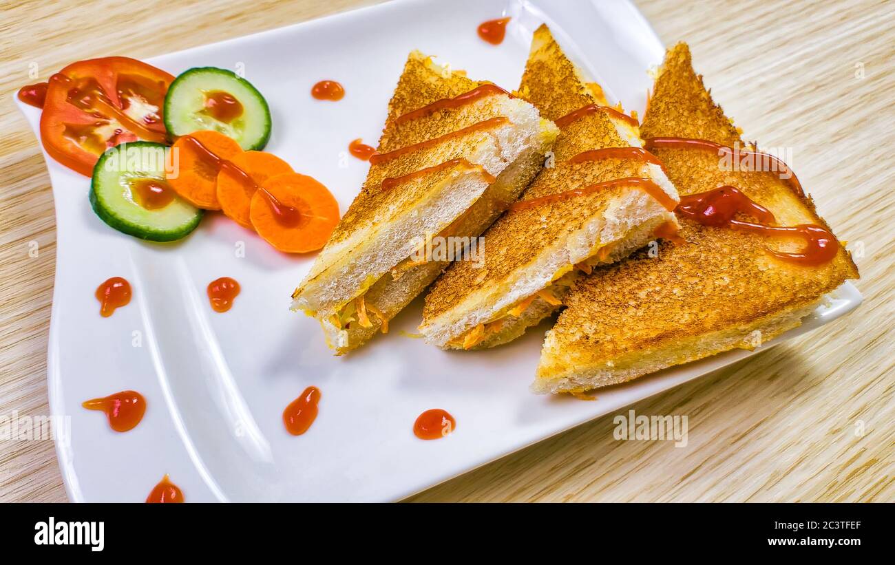 Crispy toasted Vegetable sandwiches garnished with Ketchup along with sliced vegetables. Stock Photo