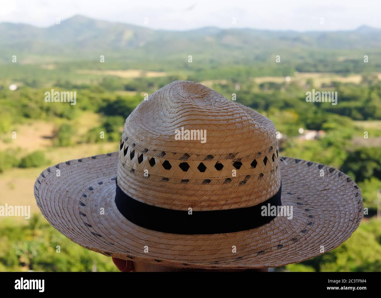 The tourist in the traditional hat is admiring views from the tower on the sugar plantation Iznaga, Cuba. Stock Photo
