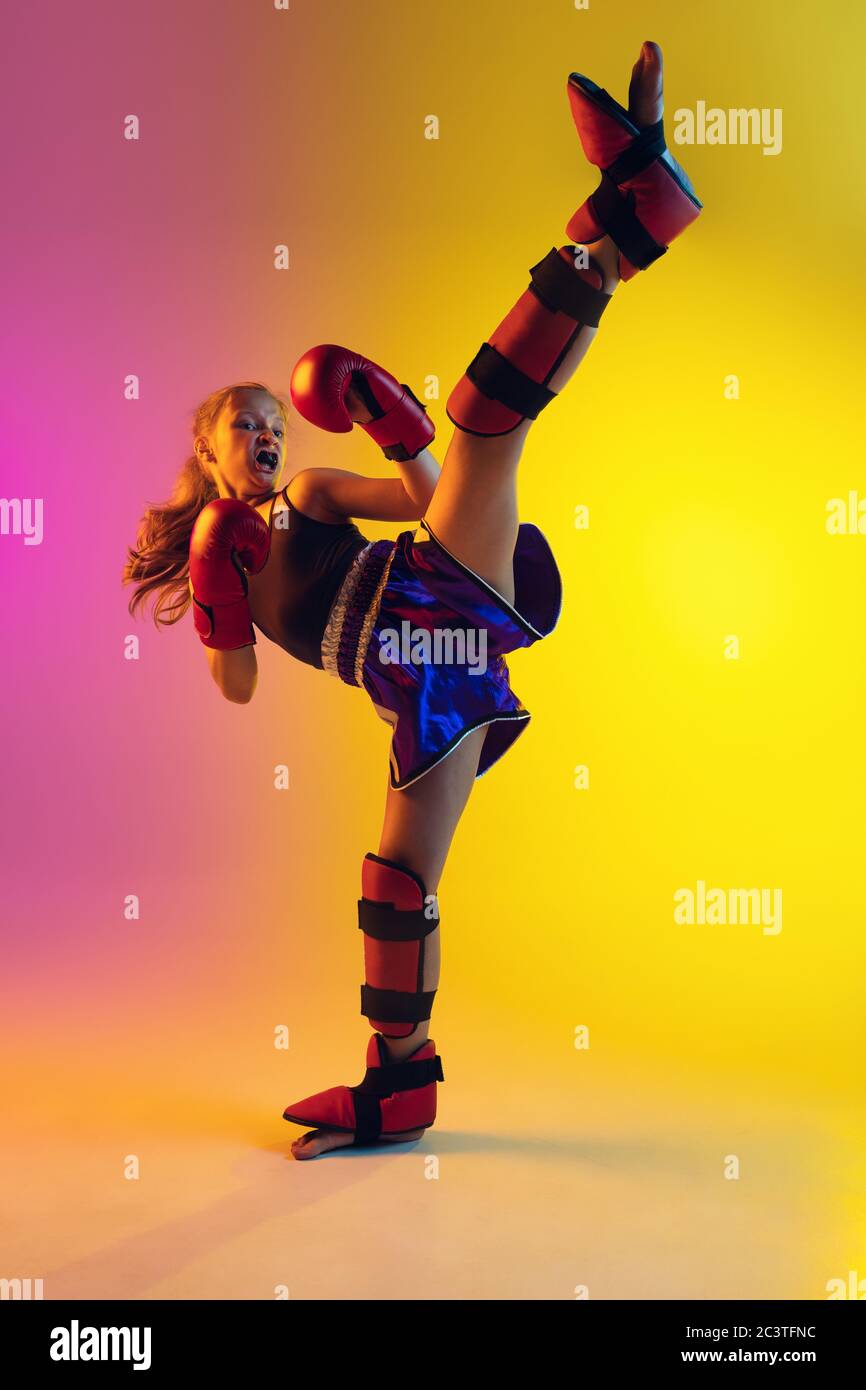 Little caucasian girl, kick boxer on gradient background in neon light