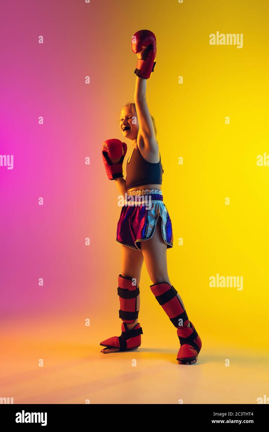 Little caucasian girl, kick boxer on gradient background in neon light