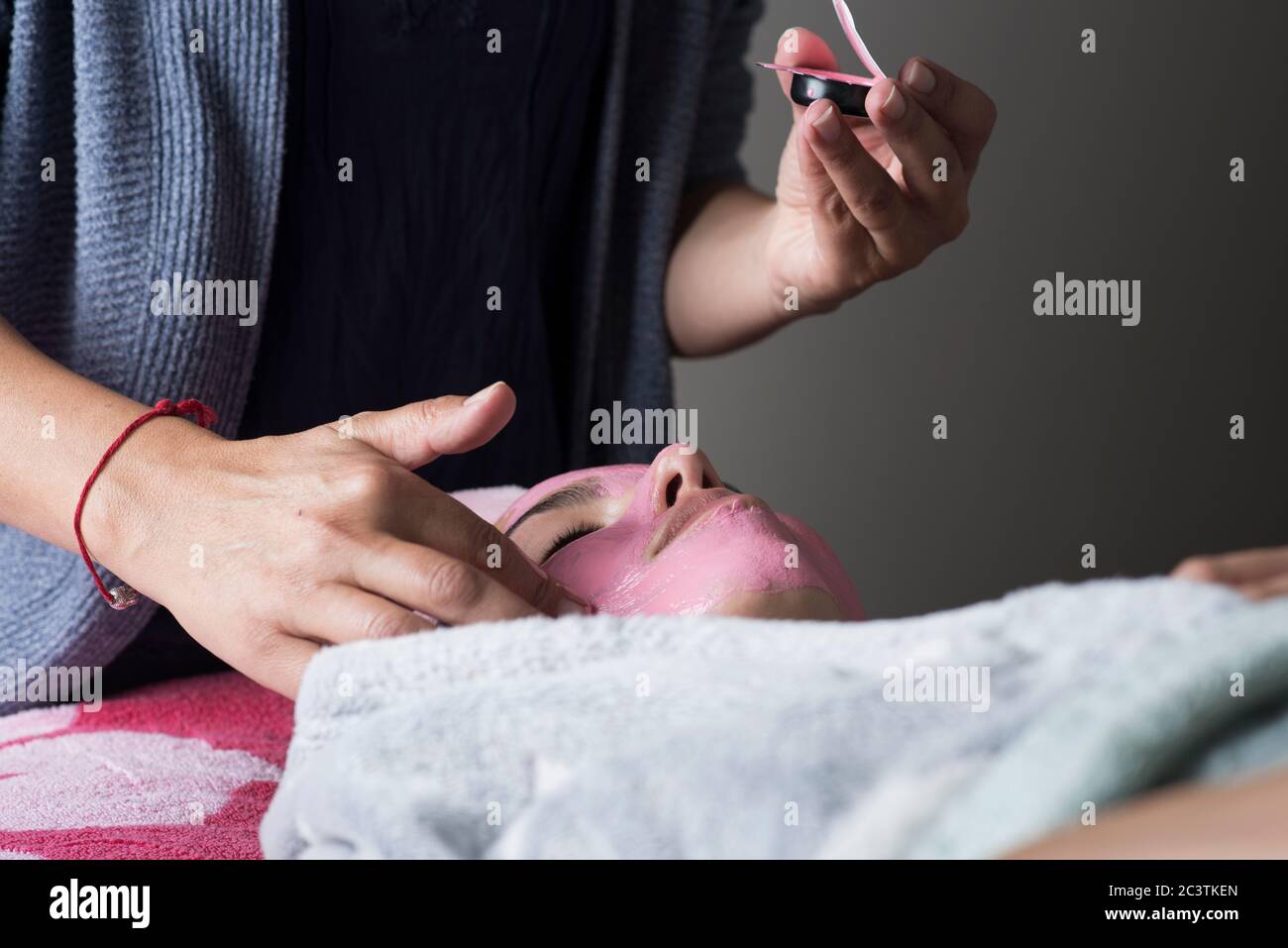 Lockdown beauty treatment, therapist applying  a face mask at home during Covid 19 lockdown Stock Photo