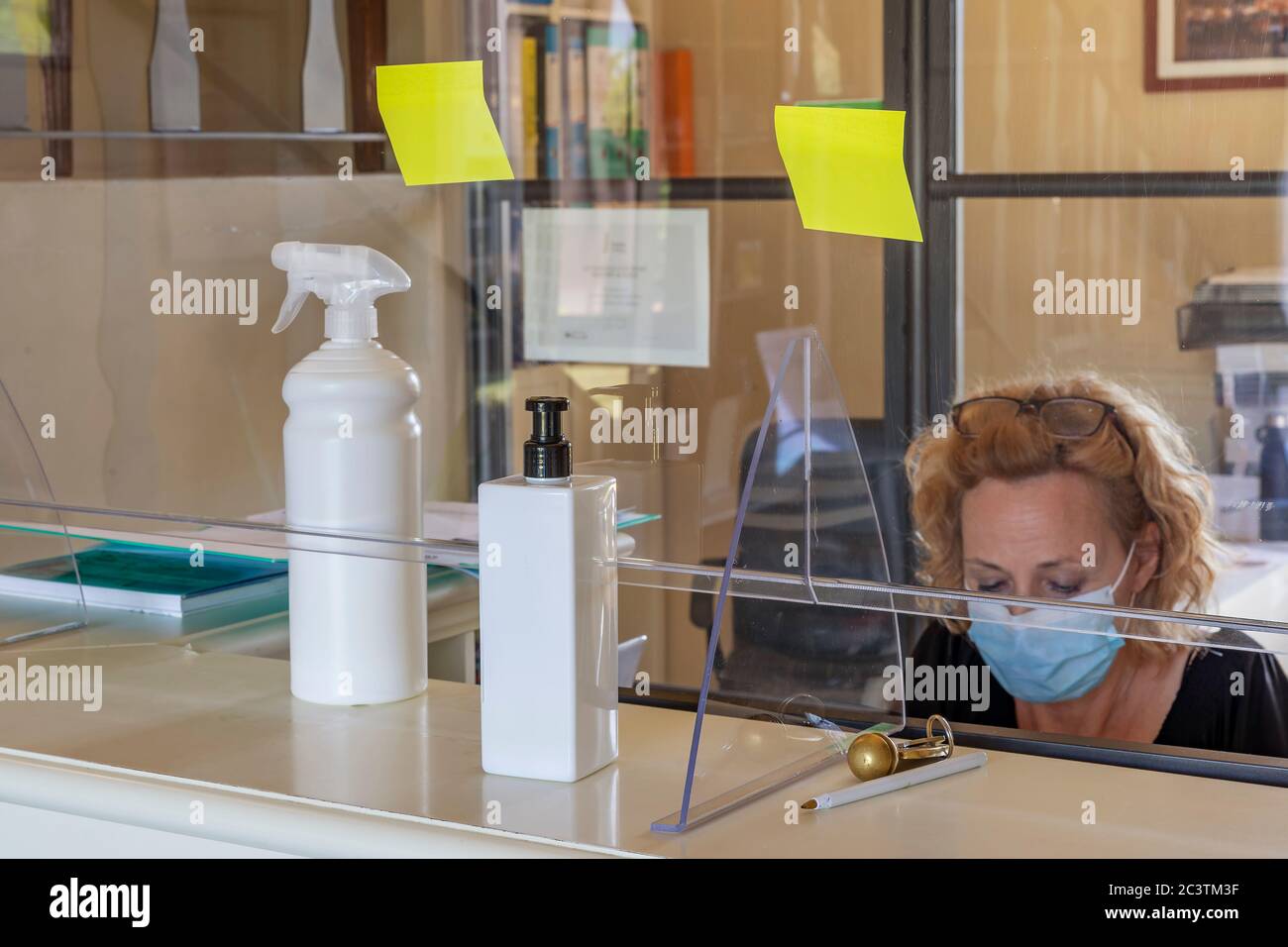 The new way of working imposed by the needs to avoid possible contagions from Covid-19 coronavirus, with plexiglass screen and mask Stock Photo