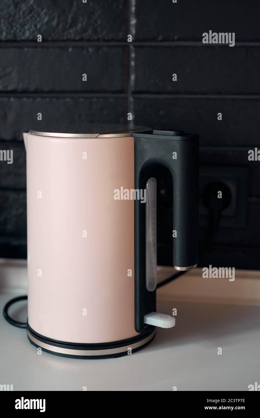 Boiling modern electric kettle. Minimalist interior design. Stylish kitchen. Black brick wall in a designer minimalist room interior of an architect. Stock Photo