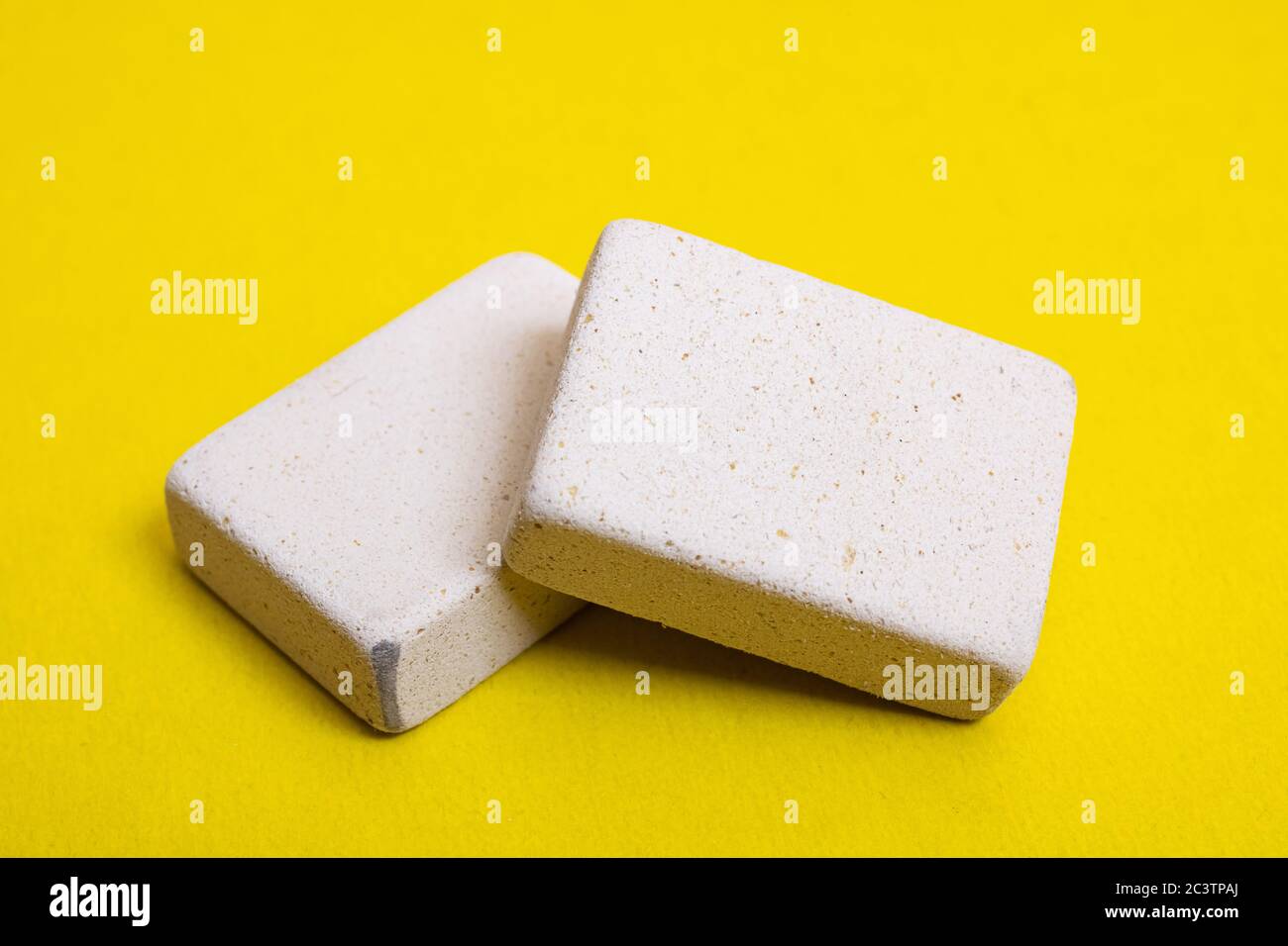 Two pencil erasers on a yellow background close up Stock Photo