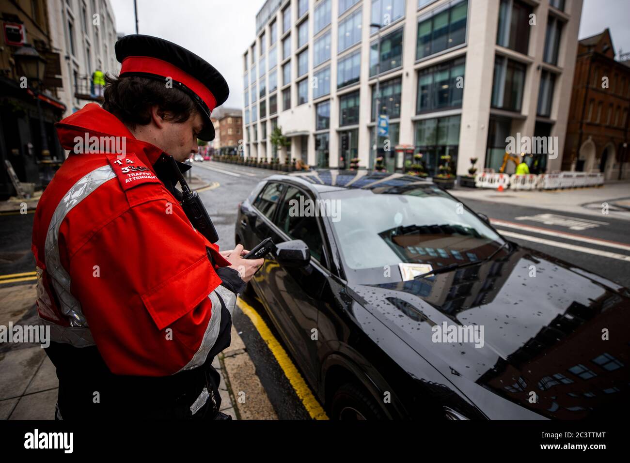 A traffic warden places a warning ticket on a vehicle in Belfast city centre as the lockdown suspension of on-street parking charges in Northern Ireland is set to be lifted. Wardens will issue 'warnings' to prepare the public for the return of charges and fines on June 29. Stock Photo