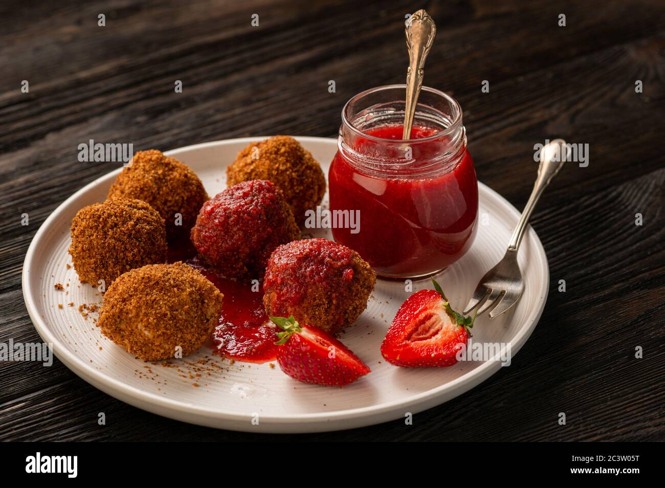 Homemade cottage cheese balls, hungarian sweet dessert served with strawberry mousse. Stock Photo