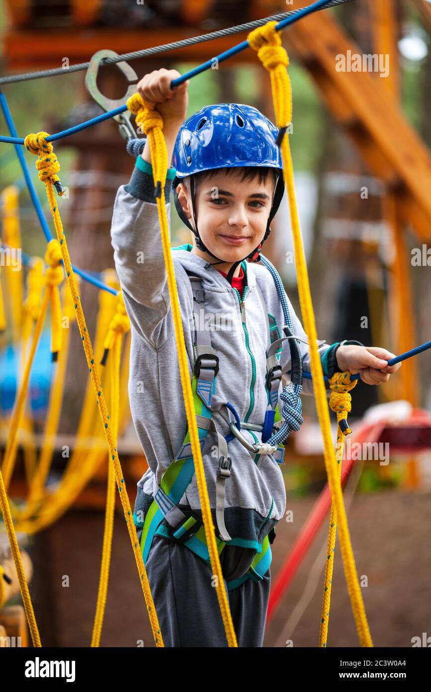 Young boy climbing pass obstacles in rope. Child in forest adventure