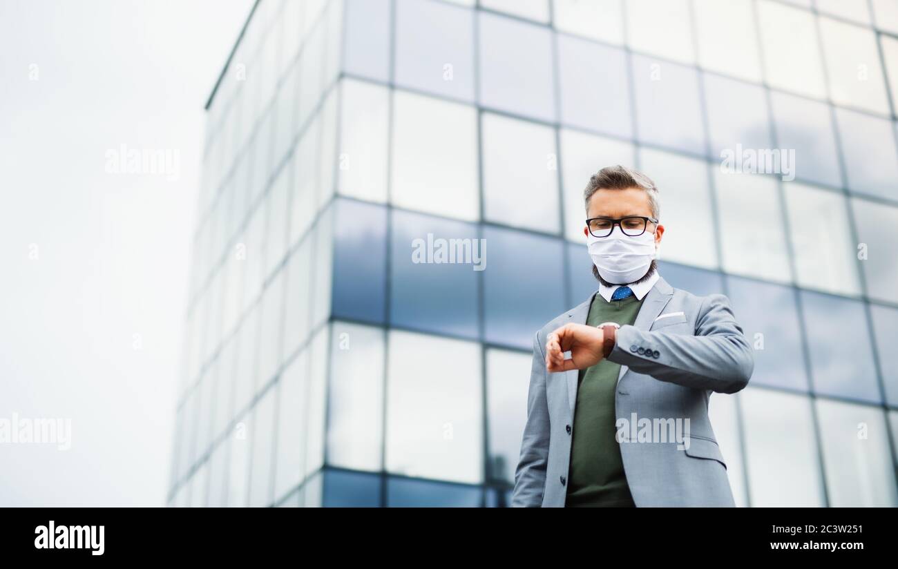 Low-angle view of businessman standing outdoors, wearing face mask at the airport. Stock Photo