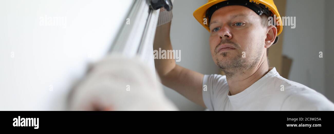Builder helmet measures wall level with building Stock Photo