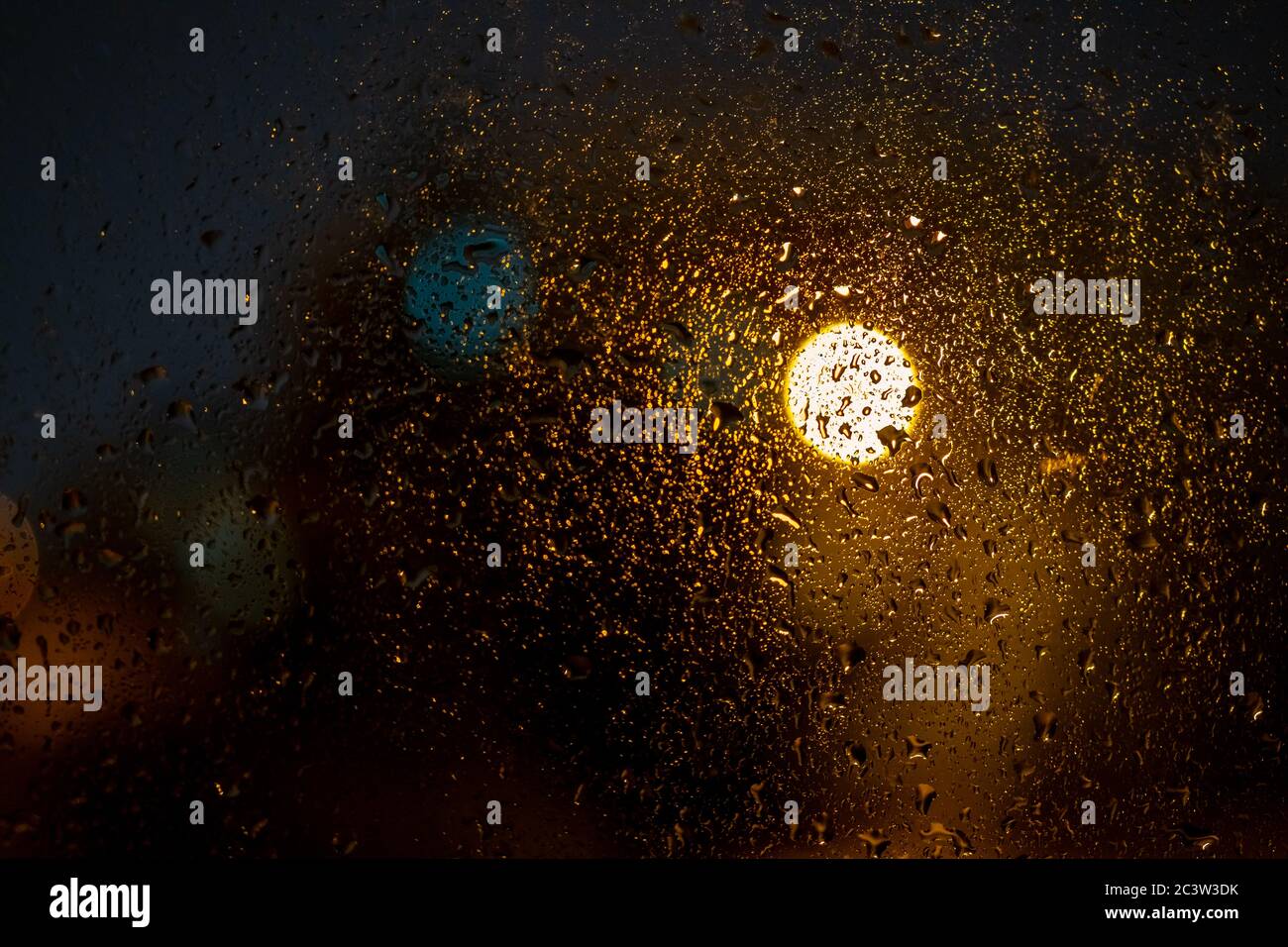 Raindrops on a window with the city lights at night, abstract blurred ...