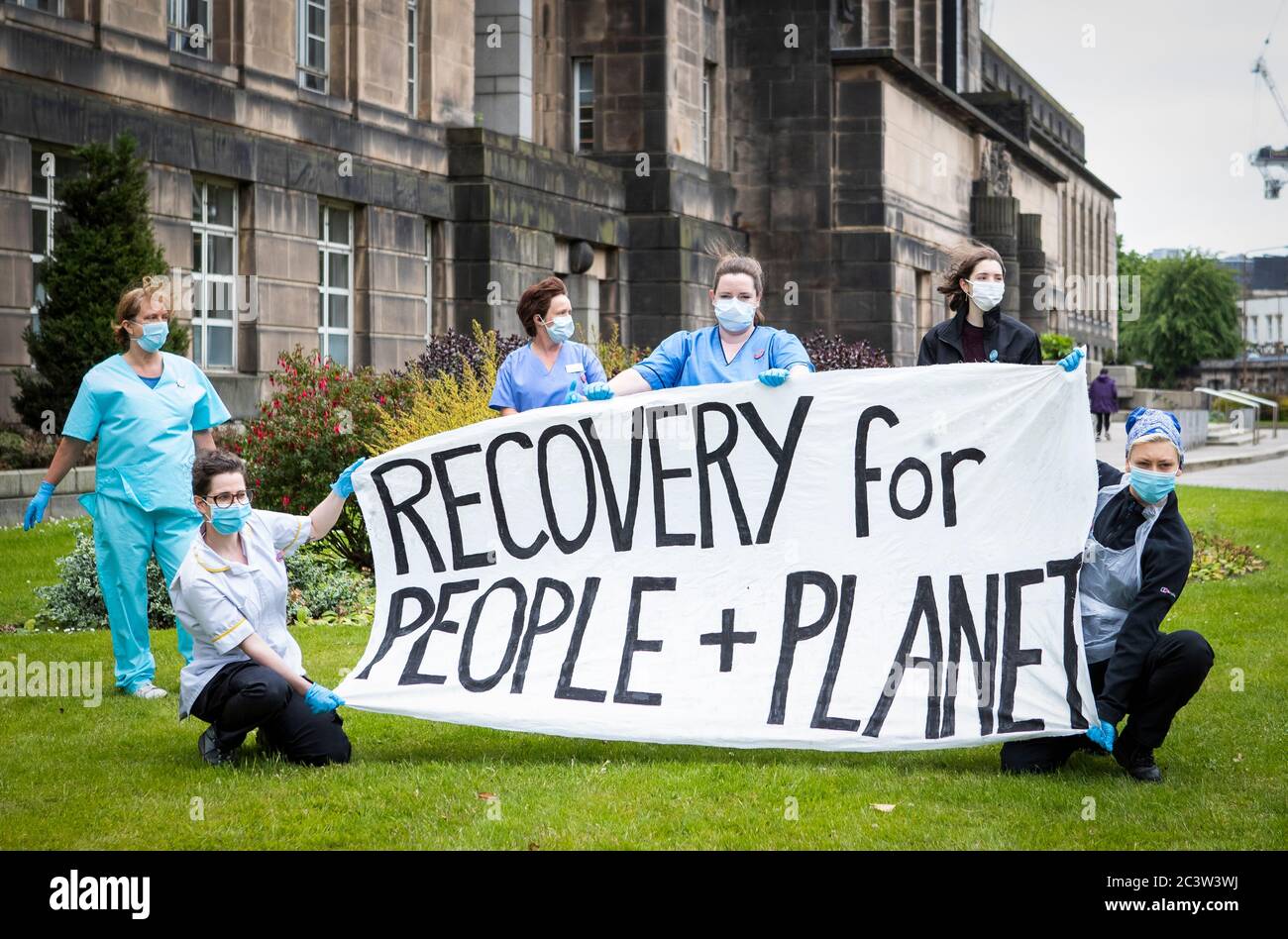 Key worker protesters, including a cleaner, a doctor and a carer, as well as Scottish Youth Climate Strikers, hold a banner saying 'Recovery for People and Planet' outside St Andrew's House, the headquarters of the Scottish Government, in Edinburgh, during a protest organised by Friends of the Earth. Stock Photo