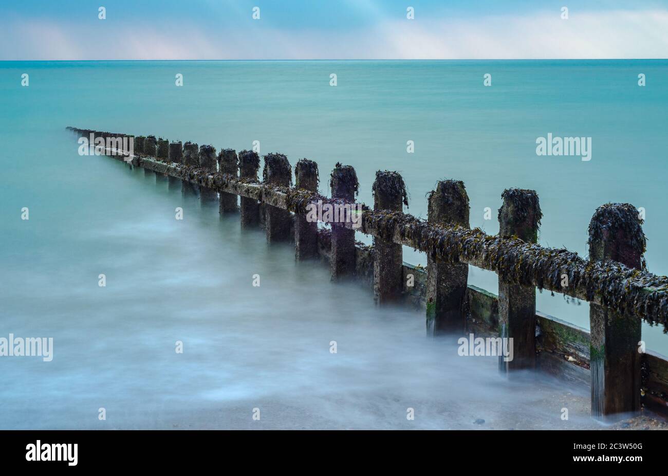 Misty effect of the sea surrounding a groyne on a beach at high tide. Stock Photo