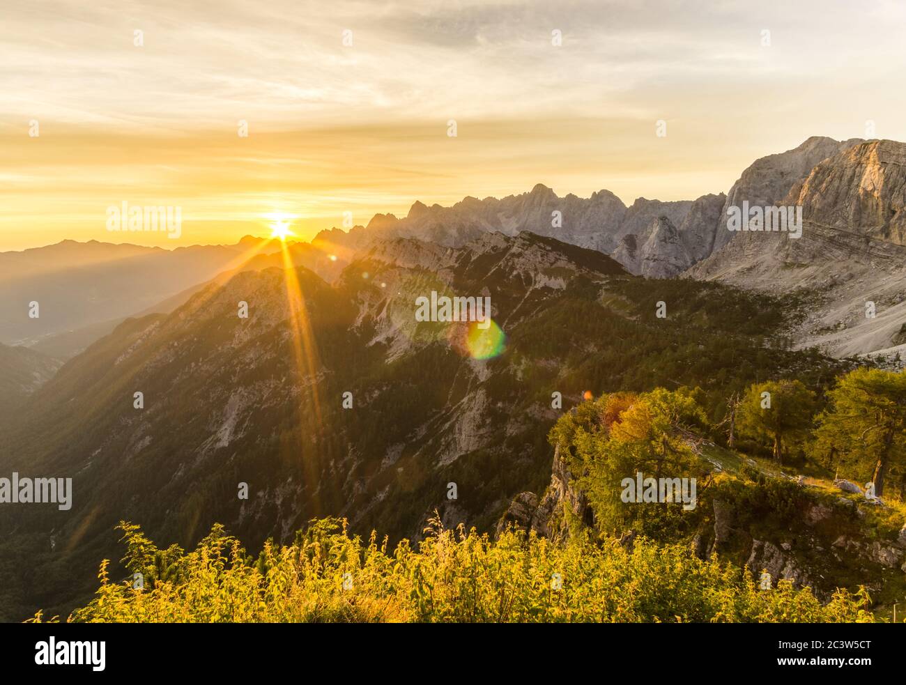Amazing sunrise in the mountains. Backlight Sunlight with beautiful lens flares and sunbeams. Julian Alps, Triglav National Park, Slovenia, Mountain Stock Photo