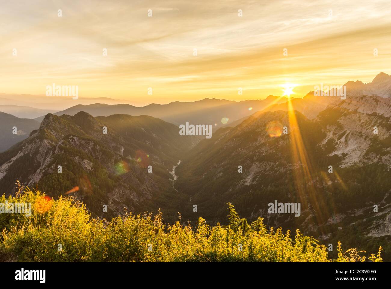 Amazing sunrise in the mountains. Backlight Sunlight with beautiful lens flares and sunbeams. Julian Alps, Triglav National Park, Slovenia, Mountain Stock Photo