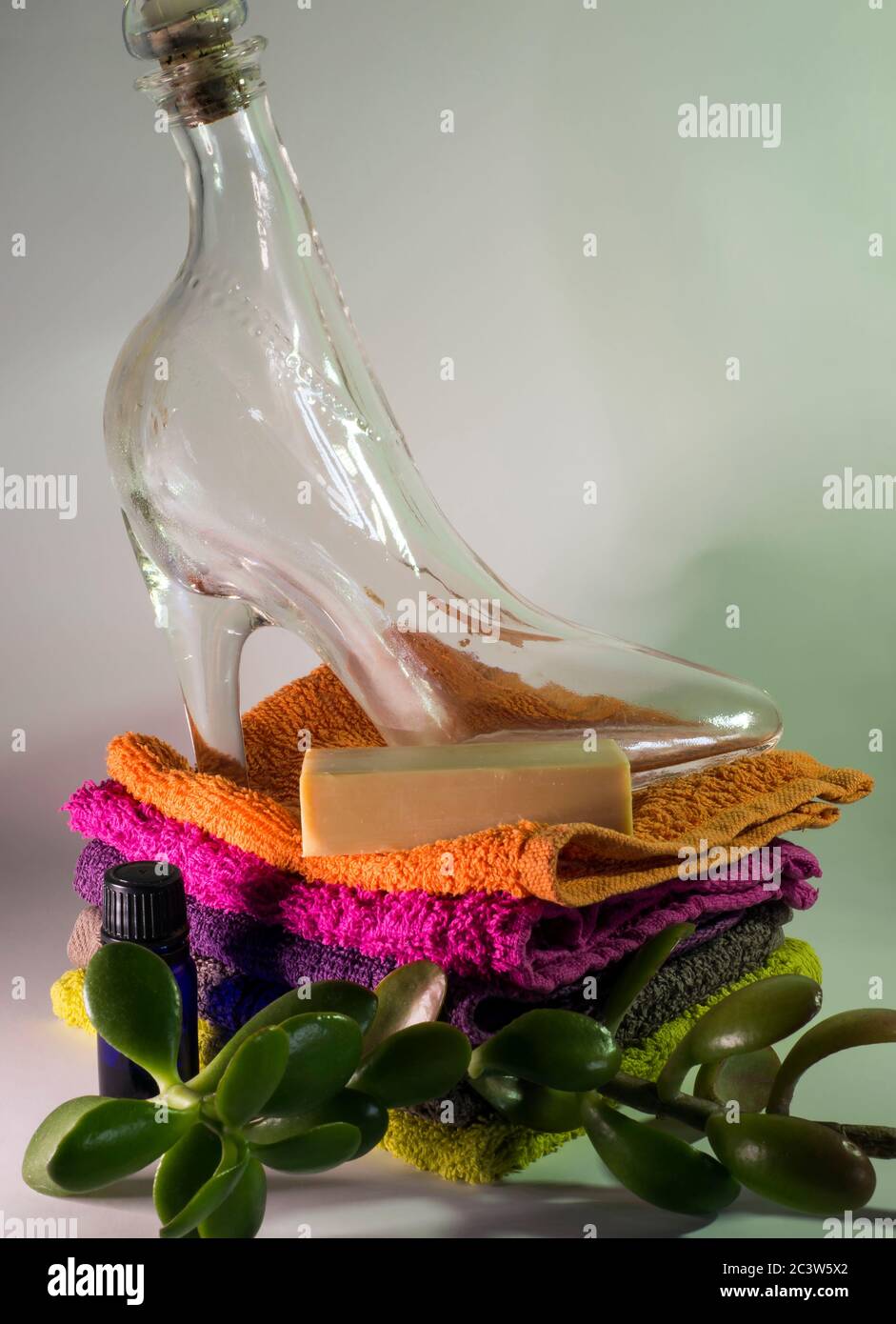 glass shoe and soap on facecloths of various shades with natural green plant Stock Photo
