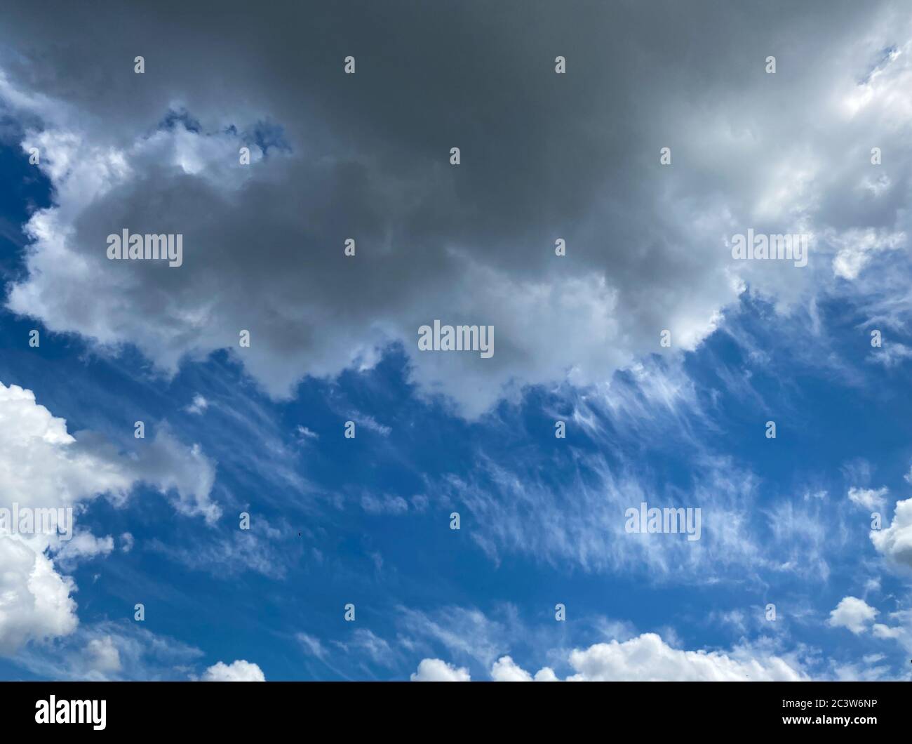 View into deep blue sky with stratocumulus and cirrus clouds on windy day announcing occasional summer rain showers Stock Photo