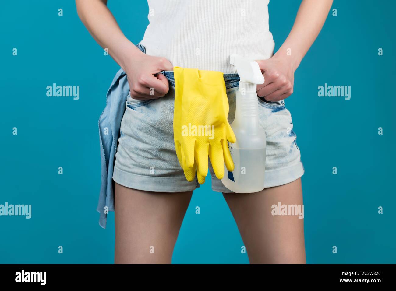Close-up of a housemaid's jeans along with a sprayer, gloves and a rag Stock Photo