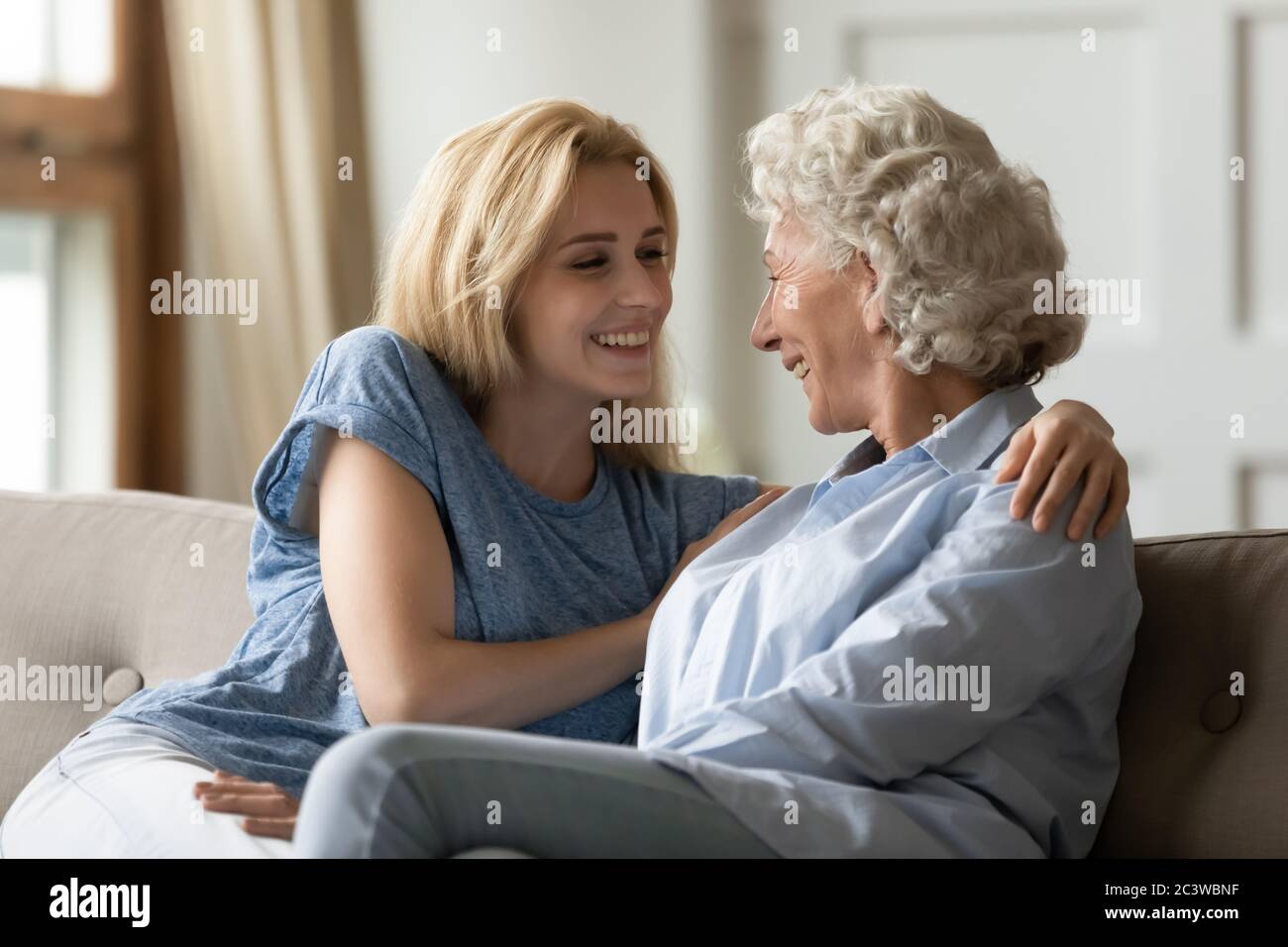 Grownup daughter hugs lovely elderly mother and enjoy pleasant talk Stock Photo