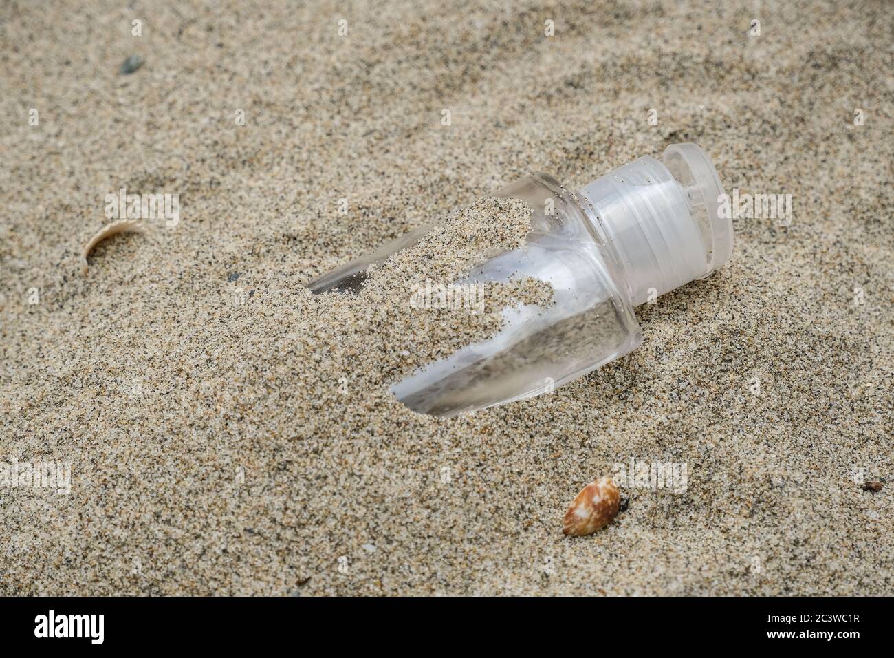 Plastic hand sanitizer,discarded garbage on sea coast,coronavirus covid pollution disease,dirty ecosystem Stock Photo