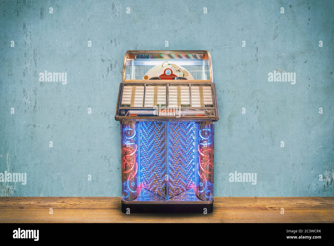 Colorful vintage jukebox in front of a blue weathered wall on a wooden floor Stock Photo