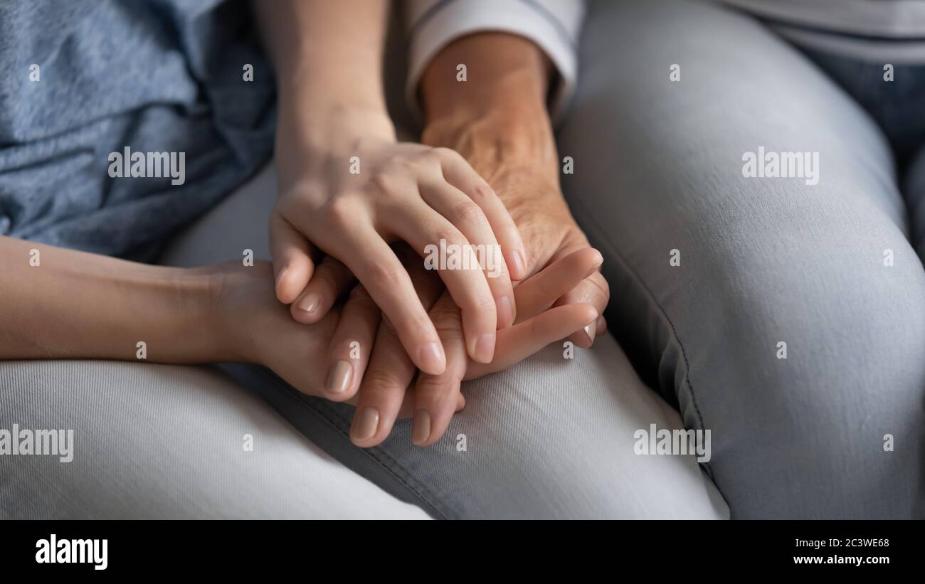 Adult daughter holds hand of old mother express support closeup Stock Photo