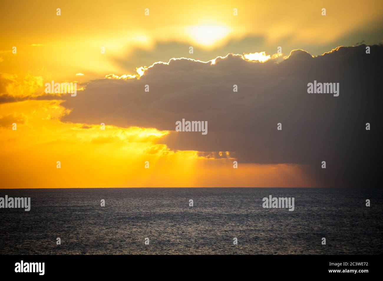 Light from the sun rays piercing dark dramatic clouds over the sea at ...