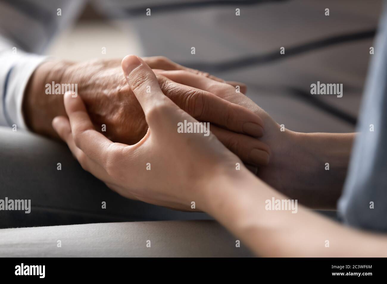 Grownup daughter holding hand of elderly mother express protection Stock Photo